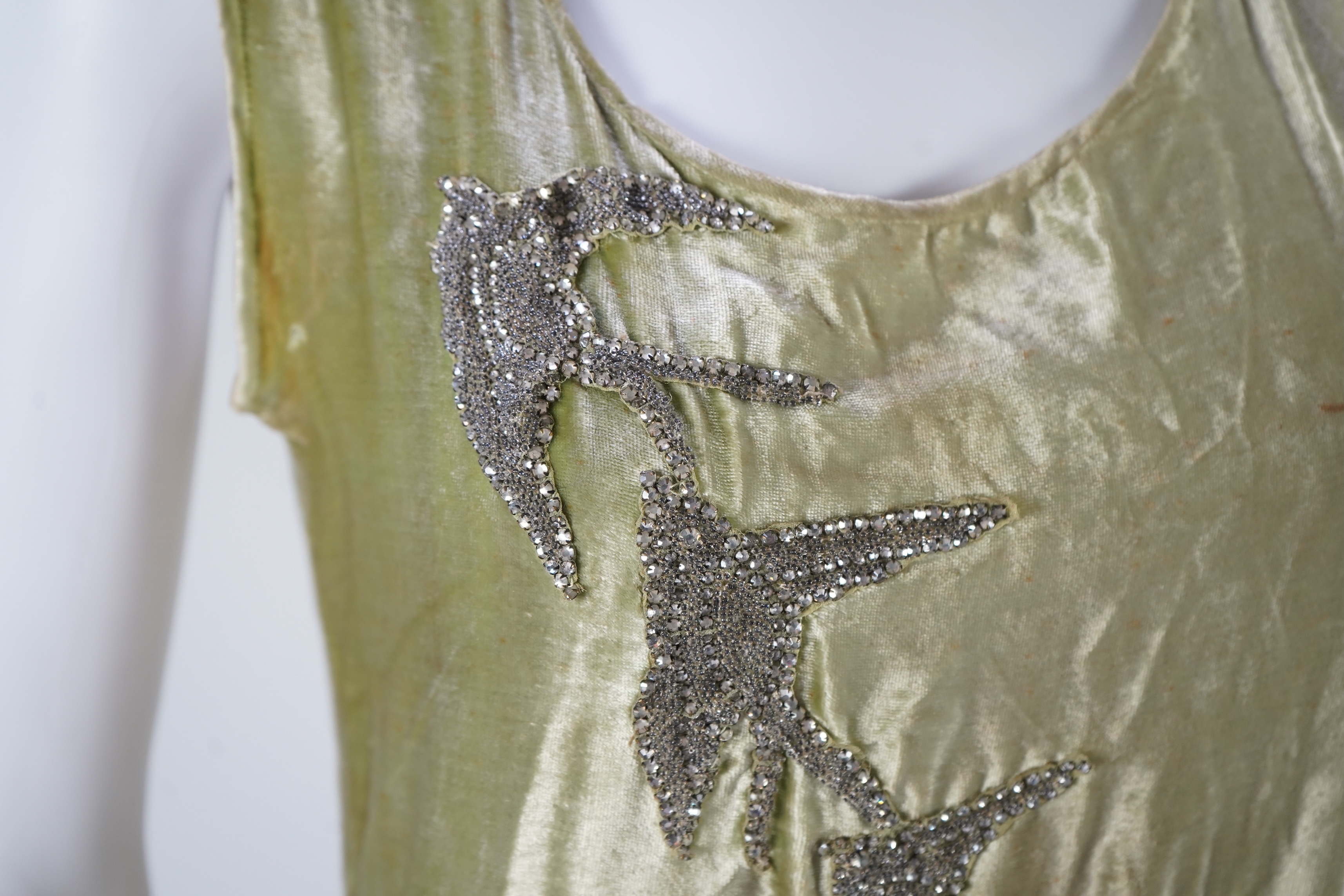 A late 1920’s early 30’s green panne silk velvet evening dress, bias cut, with large diamanté ornamentation and bow on the hip, bust 36 inches, length 55inches. Condition - there is a small hole on the front near arm hol